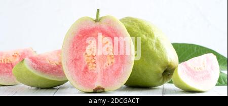 Nahaufnahme von köstlichen schönen roten Guava mit frischen grünen Blättern isoliert auf weißem Tischhintergrund, Studio-Tisch mit Kopieplatz aufgenommen. Stockfoto