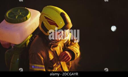 Feuerwehrmann mit Kanister auf dem Rücken in der Nacht. Feuerübung. Hochwertige Fotos Stockfoto