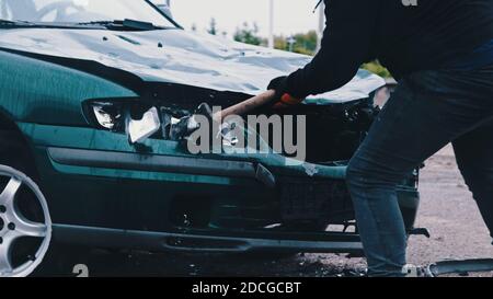 Nahaufnahme, Mann Hand brechen Auto Lichter mit großen Hammer. Hochwertige Fotos Stockfoto