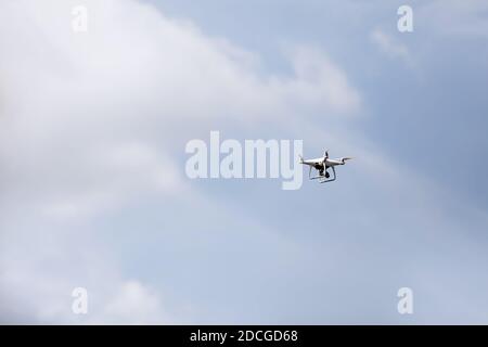 Quadcopter Drohne in Himmel. Kleine Drohne fliegt im Himmel und nimmt Videos und Fotos auf. Fernbedienung Luftzufuhr und Spion. Selektiver Fokus Stockfoto