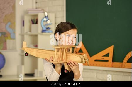 Wie ich den Sommer verbrachte. Anreise mit dem Flugzeug. Träumen Sie weiter. Schulmädchen spielen Holz Spielzeug Flugzeug. Fliegen Sie im Flugzeug. Studium der Geographie. Weltweit. Träume vom Reisen. Zurück zur Schule. Geschichte über Sommerferien. Stockfoto