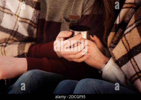 Glückliches romantisches Paar in der Liebe im Freien eingewickelt in einem karierten warm mit Tee an einem kalten Herbsttag, das Konzept der gegenseitigen Liebesbeziehungen. Stockfoto