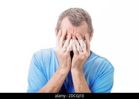 Portrait von enttäuschten Mann mittleren Alters, deckt Gesicht mit seinen Händen, Blick nach unten depressiv. Älterer Mann, der an emotionalem Zusammenbruch und Depression leidet Stockfoto