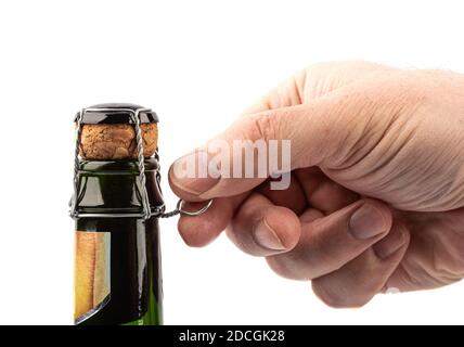 Die Hand des Mannes öffnet eine Flasche Champagner. Der Mann entschrauben das Sektmuzlet. Champagner-Flasche auf weißem Hintergrund. Stockfoto