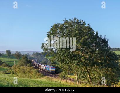 GB Railfeight Baureihe 66 Lokomotive 66747 Passing Coniston Cold in Das Aire-Tal mit einem Güterzug leerer Aggregate Trichter Stockfoto