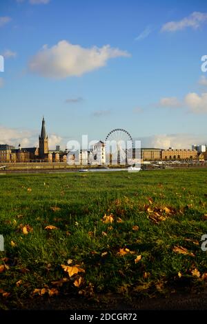 Blick über den Rhein vom Ortsteil Oberkassel, mit weißem Burgturm, Riesenrad und vorbeifahrenden Schiff. Sonniger Herbsttag. Stockfoto