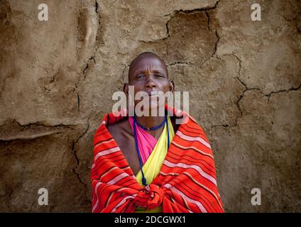 Maasai Frau, die vor einer lehmwand steht, Rift Valley Province, Maasai Mara, Kenia Stockfoto