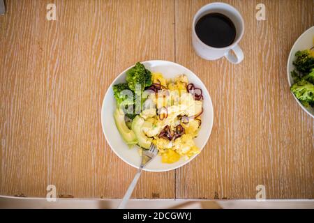 Brokkoli und Rühreier mit Avocado-Scheiben auf Holztisch Stockfoto