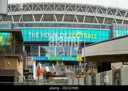 London, Großbritannien. 21. November 2020. Die Statue von Bobby Moore, Englands 1966-WM-Siegerin, blickt hinunter auf die Arbeit, die ikonischen Rampen auf dem Wembley Way, die zum Wembley Stadium führen, abzureißen. Die Rampen, auch Pedalwege genannt, werden seit 46 Jahren von Fans genutzt, die Fußballspiele und andere Veranstaltungen im Stadion besuchen. Ein neuer Satz Stufen (teilweise konstruiert, unten links gesehen) ersetzt sie und wird für 2021 zu einem Preis von £18m an Ort und Stelle sein. Kredit: Stephen Chung / Alamy Live Nachrichten Stockfoto