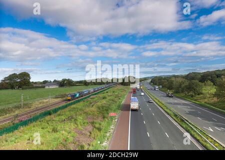 Direct Rail Services Klasse 88 BI-Modus Elektrische Lokomotive 88006 Schleppen eines Containerfrachtzuges auf der Hauptlinie der Westküste Über die Autobahn M6 Stockfoto