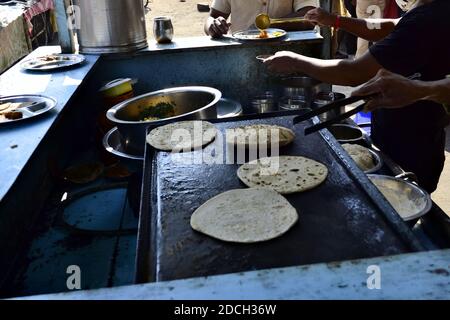 Mann, der Chapati macht. Indischer Street Food Stand. Roti mit Curry zum Frühstück auf dem Straßenmarkt am Morgen. Stockfoto