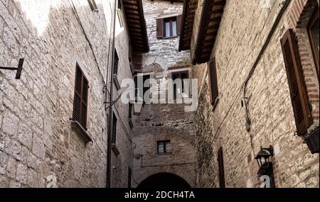 Eine schmale Gasse eines mittelalterlichen italienischen Dorfes mit Steingebäuden, Holzdächern und Fenstern (Gubbio, Italien, Europa) Stockfoto