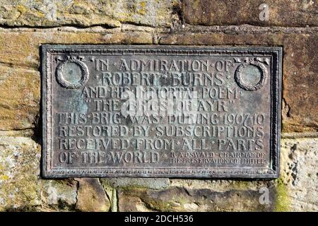 Metalltafel an Robert Burns auf der Auld Brig Ayr, Ayrshire, Schottland, die Worte sind "in Bewunderung von Robert Burns und seinem unsterblichen Gedicht die Brigs von Ayr. Diese Brig wurde im Jahr 1907-10 restauriert durch Abonnement aus allen Teilen der Welt erhalten. ' Stockfoto