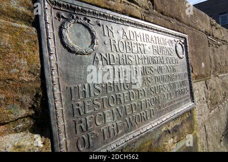 Metalltafel an Robert Burns auf der Auld Brig Ayr, Ayrshire, Schottland, die Worte sind "in Bewunderung von Robert Burns und seinem unsterblichen Gedicht die Brigs von Ayr. Diese Brig wurde im Laufe des Jahres 1907-10 durch Abonnement aus allen Teilen der Welt erhalten restauriert. ' Stockfoto