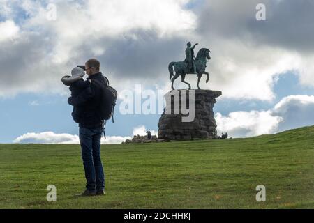 Vater und Baby machen Selfie-Fotos an der Kupferpferd-Statue von George III, die ein Ende des langen Spaziergangs im Windsor Great Park, Berkshire, Großbritannien, markiert Stockfoto