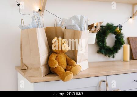 Weiches Spielzeug Bär in der Nähe Handwerk Papiertüten und Weihnachtskranz Stockfoto