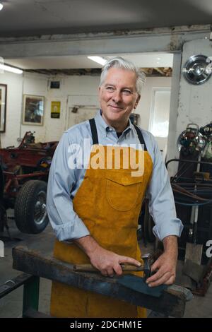 Mann, der in einer Werkstatt am Auto arbeitet. Stockfoto