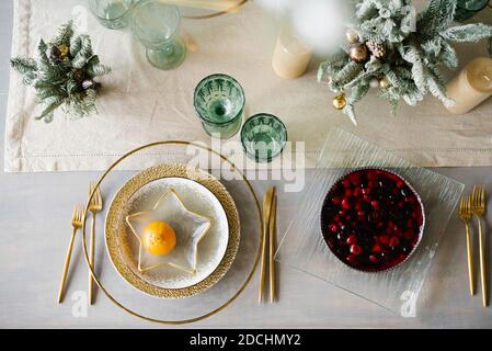 Stilvolles weihnachtliches Dinner. Goldene und weiße Platten, eine sternförmige Platte mit Mandarine. Berry Pie auf dem Tisch Stockfoto