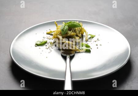 Spaghetti mit Pesto-Sauce, Basilikum, Nüsse und Parmesan isoliert auf einem Teller. Nahaufnahme. Selektiver Fokus Stockfoto