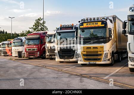 Reihe von verschiedenen Firmen-Lkw auf einem LKW-Parkplatz über Nacht somwehere entlang der Autobahn E30 geparkt. Deutschland - 14. Juni 2019 Stockfoto