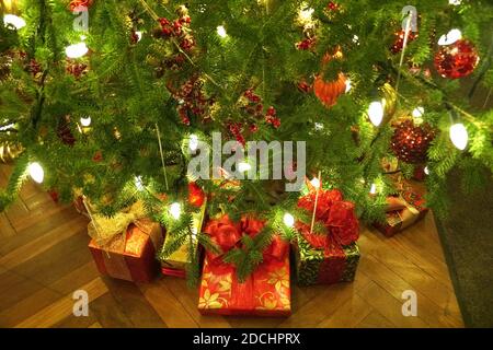Schachteln mit Geschenken unter dem Weihnachtsbaum mit Lichtern Stockfoto