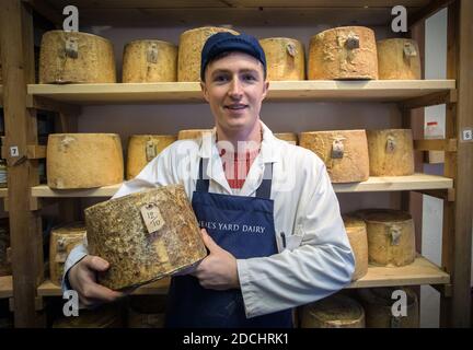 Junger Mann, der Käse bei der Neal s Yard Dairy auf dem Borough Market in Southwark, London, England verkauft. Stockfoto