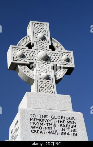 Ballantrae, South Ayrshire, Schottland, Großbritannien, Kriegsdenkmal, das Denkmal steht unter den Ruinen der Burg. Es ist ein graues keltisches Granitkreuz mit Radkopf und Bossen, die auf einem niedrigen, verjüngenden Schaft auf einem großen quadratischen Sockel liegen. Die Gedenkfeier und die Namen der Toten sind in Bleischrift auf den Gesichtern des Sockels angebracht. Die Namen der Toten aus dem 1. Weltkrieg werden nach dem Todesjahr aufgelistet, einschließlich der Namen bis 1920. Stockfoto