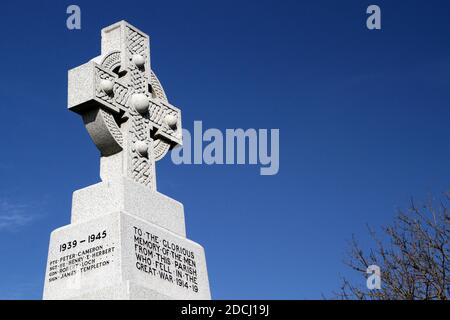 Ballantrae, South Ayrshire, Schottland, Großbritannien, Kriegsdenkmal, das Denkmal steht unter den Ruinen der Burg. Es ist ein graues keltisches Granitkreuz mit Radkopf und Bossen, die auf einem niedrigen, verjüngenden Schaft auf einem großen quadratischen Sockel liegen. Die Gedenkfeier und die Namen der Toten sind in Bleischrift auf den Gesichtern des Sockels angebracht. Die Namen der Toten aus dem 1. Weltkrieg werden nach dem Todesjahr aufgelistet, einschließlich der Namen bis 1920. Stockfoto