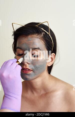 Die Kosmetikerin trägt eine feuchtigkeitsspendende Maske auf das Gesicht des Kunden auf. Stockfoto