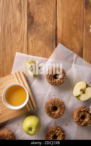 Gebackene Apfelmost-Donuts mit Apfelmost und Früchten auf Backblechen auf natürlichem Holztisch. Bereit, Snack zu essen. Kleine Partie hausgemachtes Essen. Direc Stockfoto