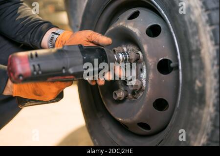 Kfz-Mechaniker Arbeiter tun Reifen oder Rad Austausch mit Elektroschlüssel in der Garage der Reparatur-Service-Station. Hochwertige Fotos Stockfoto