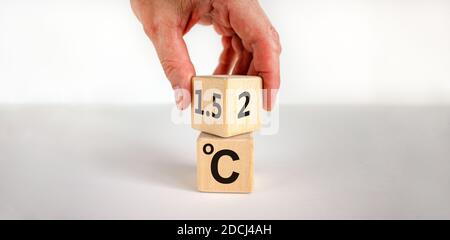 Symbol für die Begrenzung der globalen Erwärmung. Männliche Hand dreht einen Würfel und ändert den Ausdruck '2 C' in '1.5 C', oder umgekehrt. Konzept. Schöne weiße Backgr Stockfoto