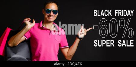 Schöner Mann hält Stapel von Papiertüten mit Inschrift schwarzen freitag. Black friday Konzept Stockfoto