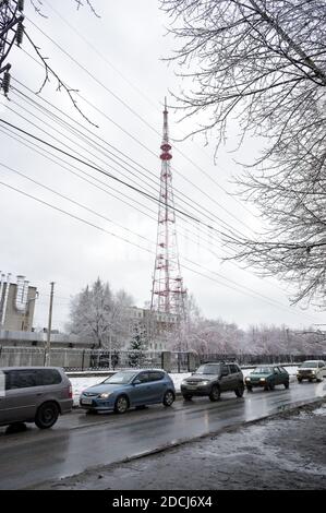 Autos fahren in einer Reihe auf einer schmutzigen Straße vor dem Hintergrund eines Fernsehturms in der Stadt Nowosibirsk. Russland. Stockfoto