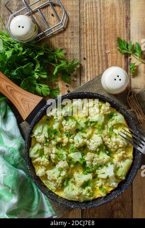 Diät Frühstück oder gesundes Mittagessen. Eieromelett mit Blumenkohl in einer gusseisernen Pfanne auf rustikalem Holztisch. Draufsicht flach lagen Hintergrund. Speicherplatz kopieren. Stockfoto