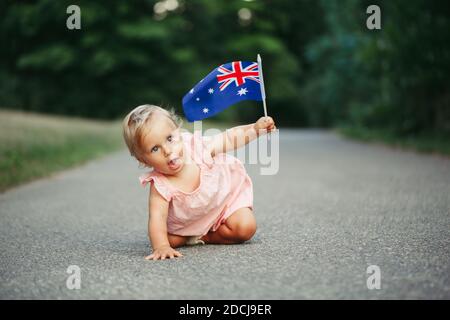 Niedlich liebenswert kaukasischen Baby Mädchen winkt australische Flagge. Lustige Kind kriechen auf der Straße im Park zu feiern Australien Tag Urlaub. Feier o Stockfoto