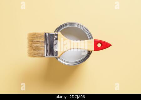 Neue natürliche Borstenbürste mit Holzgriff auf offene weiße Farbe kann über pastellgelben Hintergrund. Bau Lackierung arbeiten, Reparatur, neu dekorieren. Stockfoto
