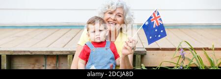 Alte Großmutter mit Enkelkind mit australischer Flagge. Alte Dame mit Kind auf dem Hinterhof winkt Australien Flagge. Familienbürger feiern Stockfoto