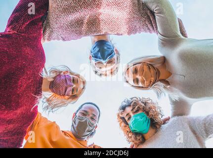 Multiethnische Gruppe von Freunden mit Gesichtsmaske in Kreis - Verschiedene Menschen unterschiedlicher Ethnien lächeln und schauen auf Die Kamera in Coronavirus ti Stockfoto