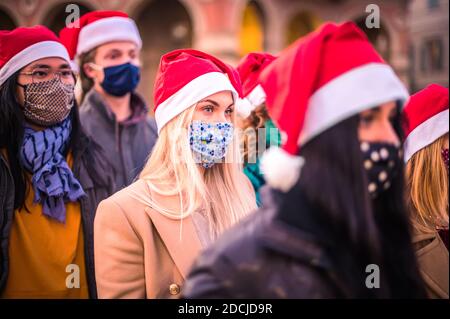 Frohe Weihnachten! Freunde Gruppe zu Fuß in der Stadt tragen Gesichtsmaske und santa Hut in Coronavirus Zeit - Fokus auf die blonde Mädchen Stockfoto