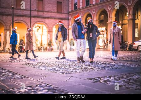 Gruppe von Menschen tragen Gesichtsmaske und santa Hut zu Fuß In der Straße in der Weihnachtsnacht in Coranavirus-Zeit -Neu Normales Lifestyle-Konzept Stockfoto