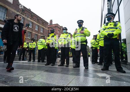 Victoria St, Liverpool, 21. November 2020: Polizeibeamte bilden eine Linie, die Anti-Lockdown-Demonstranten blockiert, während ein Mann auf sein Smartphone schaut und Aufzeichnungen macht Stockfoto