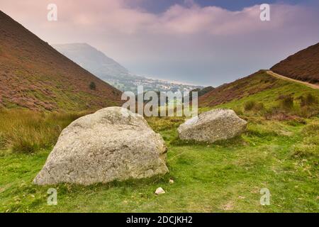 Erhöhter Blick mit Penmaenmawr und dem Irischen Meer in der Ferne und großen Felsbrocken im Vordergrund. Nordwales, Großbritannien. Stockfoto