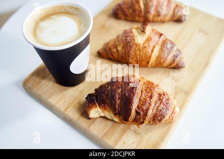Goldene frische Croissants mit Kaffee auf einem Holztablett schließen Nach oben Stockfoto