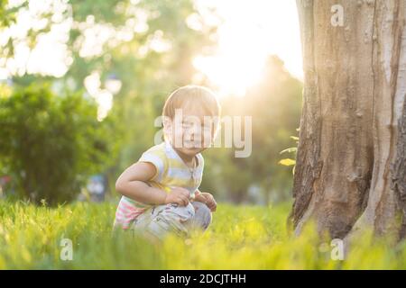 Kindheit, Natur, Sommer, Parks und Outdoor-Konzept - Porträt von niedlichen blonden kleinen Jungen in gestreiften mehrfarbigen T-Shirt mit serous, traurig Stockfoto