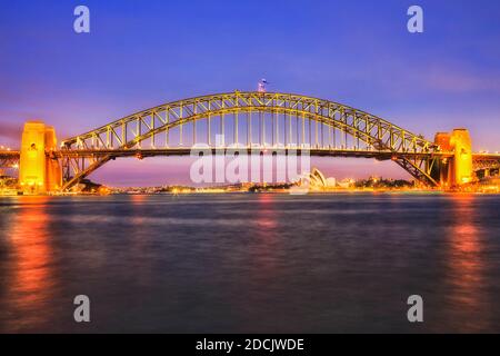 Farbenfroh beleuchtete Wahrzeichen der Stadt Sydney - die Hafenbrücke über den Hafen bei Sonnenuntergang. Stockfoto