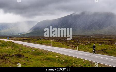 Glencoe, Schottland, UK - Juni 4, 2011: ein Radfahrer auf der A82 Straße ist durch die Weite des Rannoch Moor und die Berge von Glen Coe in den Wir in den Schatten gestellt Stockfoto