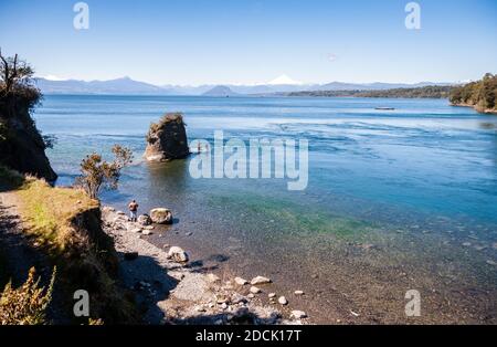 Osorno, Chile - 27. September 2009: Zwei Männer stehen beim Angeln im Lago Rupanco, mit den Vulkanbergen der patagonischen Anden dahinter. Stockfoto