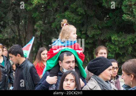 Ein Mädchen wickelte die aserbaidschanische Flagge auf die Schulter seines Vaters und sie feiern den Siegestag des Karabach-Krieges. Baku - Aserbaidschan: 10. November 2020. Stockfoto