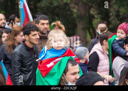 Ein Mädchen wickelte die aserbaidschanische Flagge auf die Schulter seines Vaters und sie feiern den Siegestag des Karabach-Krieges. Baku - Aserbaidschan: 10. November 2020. Stockfoto